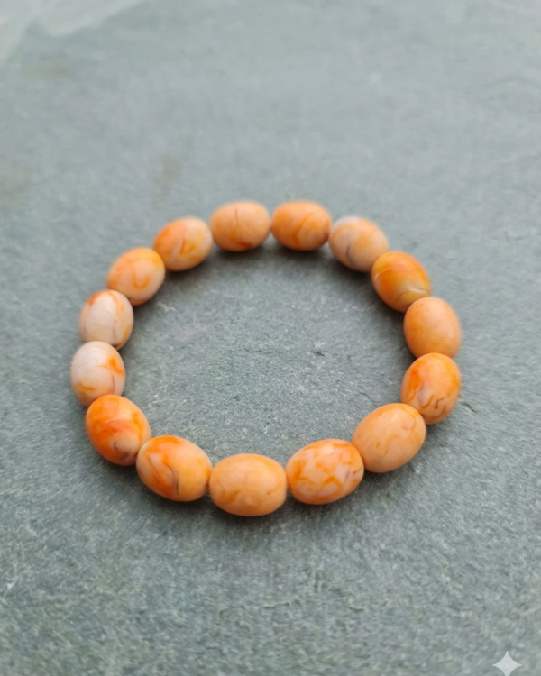 Natural orange marble-pattern beaded stretch bracelet displayed in a circular shape on a textured grey stone background.