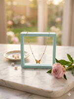 A flat lay view of a gold butterfly pendant necklace displayed against a smooth, solid light gray background, as seen in Butterfly shape pendant chain.